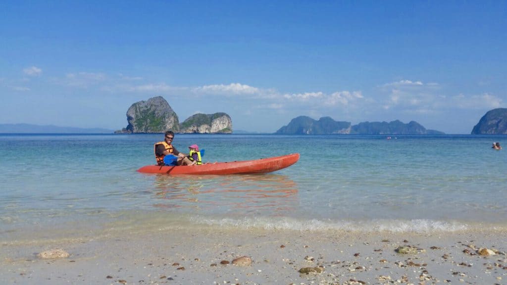 Man and child kayaking with island in the background