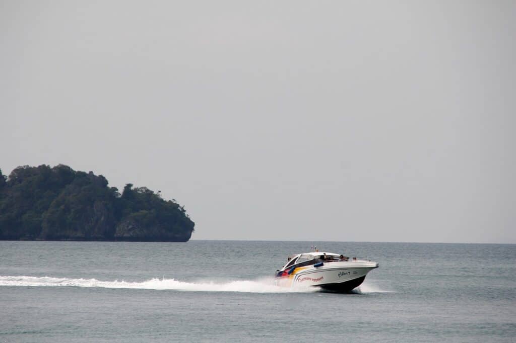 Speedboat passing an island on calm seas. How to get to Koh Phi Phi