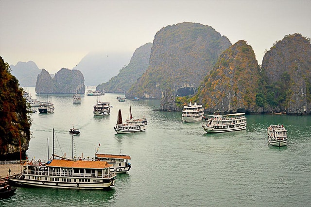 Boats sailing past karst islands in in Halong Bay