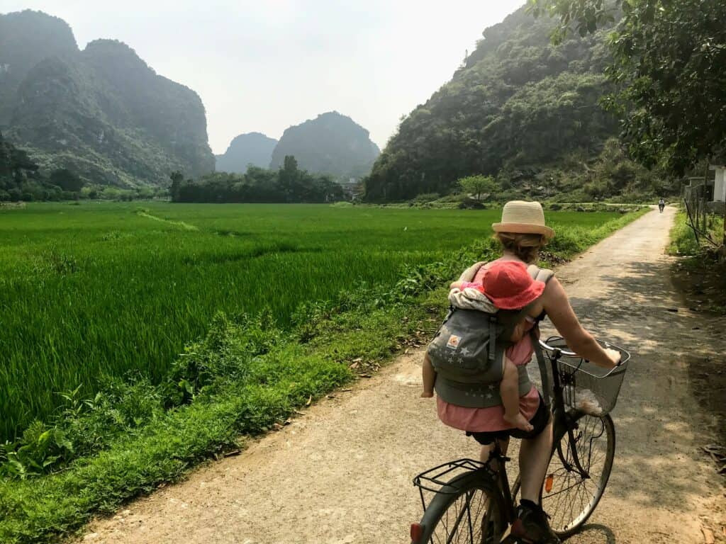 woman cycling past rice paddies on a Vietnam 10 day itinerary