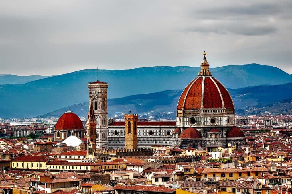 Florence skyline with domed church with red tiles. Mountains in the background. 