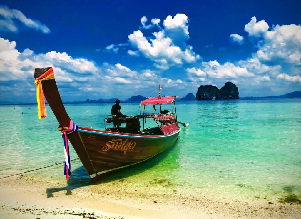 Longtail boat on the beach in Koh Ngai with island behind. Krabi with kids