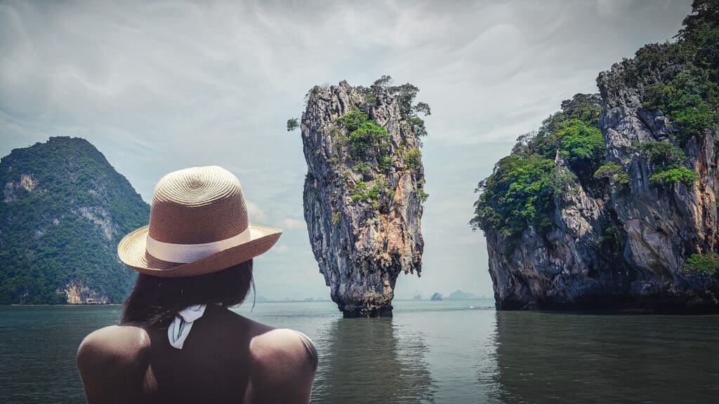 Woman looking out towards karst pinnacle of James Bond island. Krabi with kids