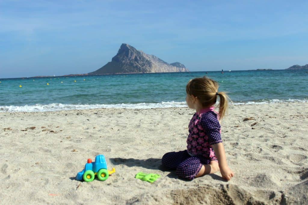 Porta Taverna one of the best beaches in Sardinia with toddler sat on the sand