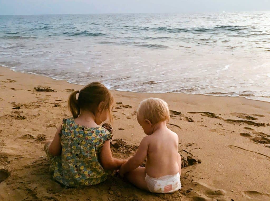 Beach in Thailand with a baby and toddler sat by the sea