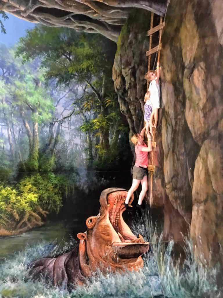 Family climbing ladder away from a hippo in 3d artwork. A great thing to do in bangkok with kids