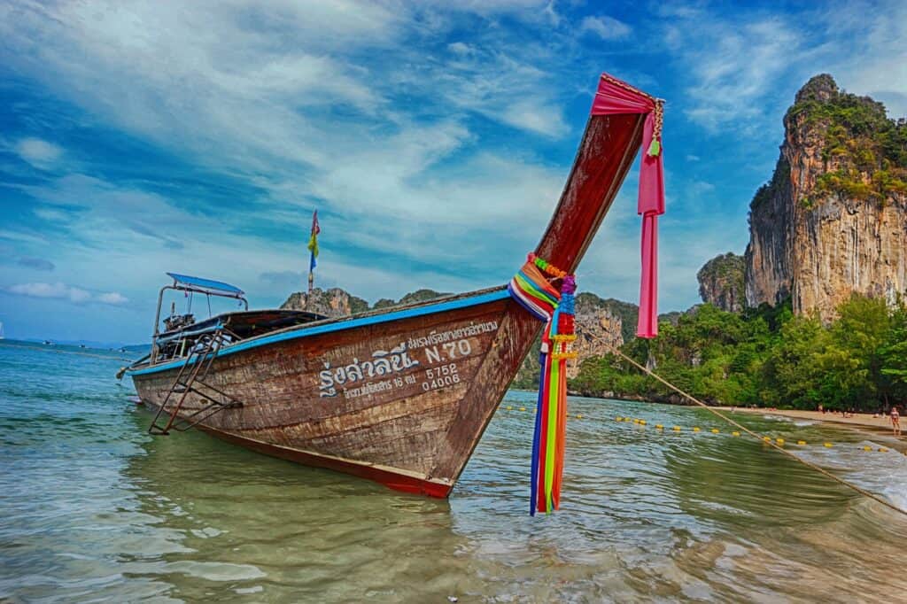 Longtail boat infront of sea and cliff. Krabi with Kids