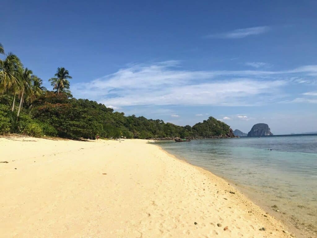 Paradise Beach on Koh Ngai island. Empty stretch of sand backed by palm trees and jungle, calm sea