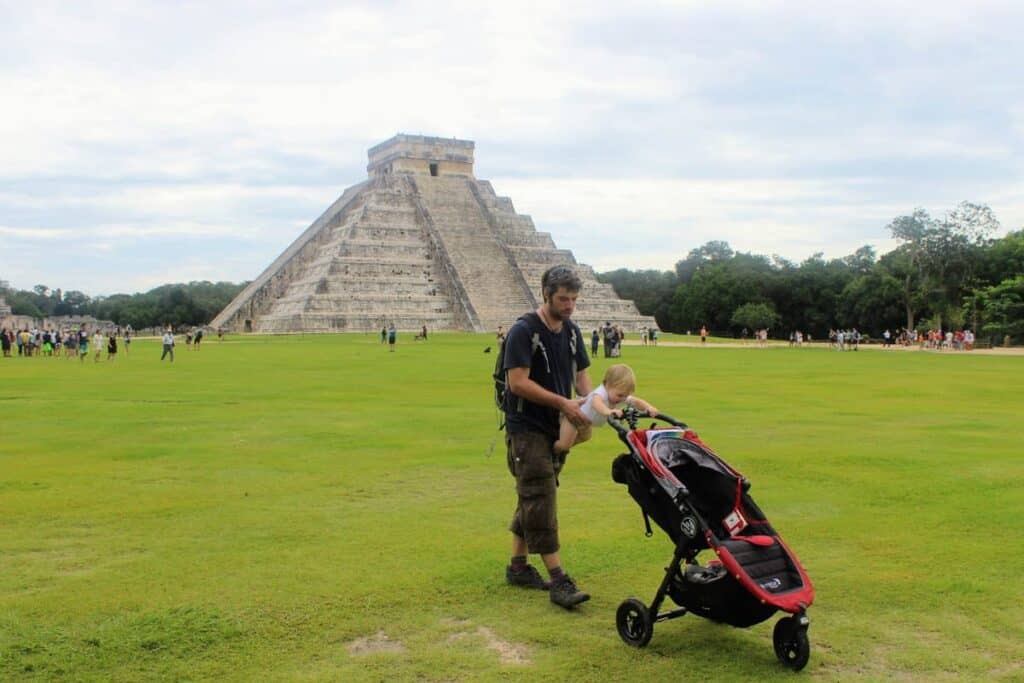Man at Chitzen Itza Mexico with a baby holding her stroller