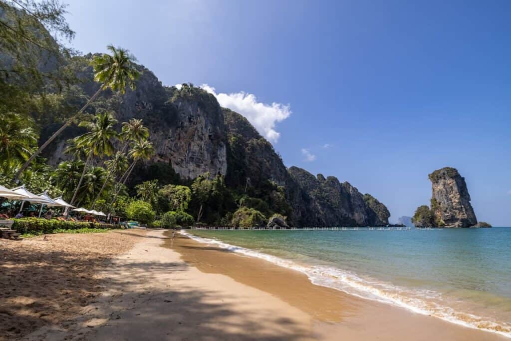 Image of Ao Nang beach with palm trees cliffs and sandy beach. taken from one of the best hotels in Ao Nang and featured in this where to stay in Aon Nang blog post.